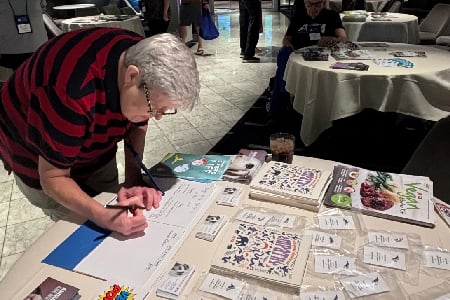 A cruise passenger signs petitions during an event with PETA staff.